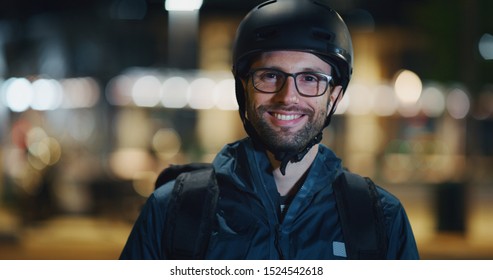 Portrait Of An Young Cyclist Wearing A Security Helmet Is Smiling In Camera Satisfied With His Race In Evening In A City Center.