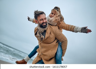 Portrait of a young dad and his cute daughter who have fun on the beach in winter. - Powered by Shutterstock