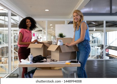 Portrait of young diverse female executives unpacking cardboard boxes in office. This is a casual creative start-up business office for a diverse team - Powered by Shutterstock