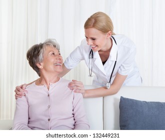 Portrait Of Young Doctor And Senior Patient Sitting On Couch