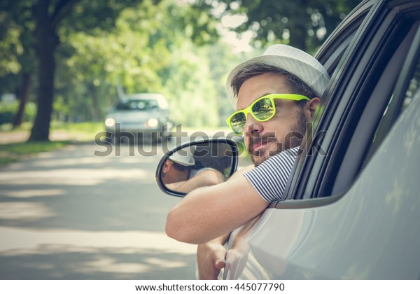 Portrait of young driver wearing
sunglasses in driverâ??s seat. Vacation and travel
concepts.