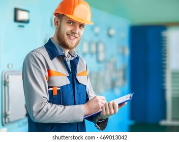 Portrait of young engineer taking notes at control room in factory - Powered by Shutterstock