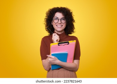 Portrait of a young entrepreneur woman making notes in a notebook smiling against a yellow background. People lifestyle concept. Creative concept idea. Creative - Powered by Shutterstock