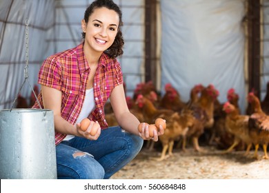 Portrait of young european woman farmer holding fresh eggs in hands in henhouse 