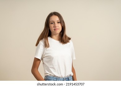 Portrait Of A Young European Woman With Healthy Clean Skin And Brown Eyes Wearing A Casual Top Looking At The Camera With A Serious Expression. Spanish Female Model With Loose Hair.