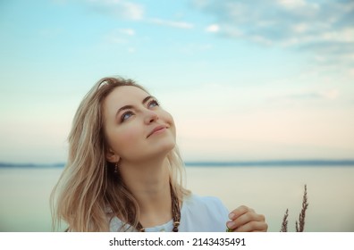 Portrait of young european woman looking up at the blue sky. Nude make-up. Beautiful girl portrait. Side view. Profile. Dream. Nature background. International woman day. Elegant style. Relaxation.