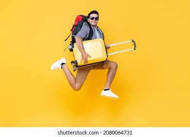 Portrait of young excited Caucasian male tourist with baggage jumping in mid-air isolated on colorful studio yellow background - Shutterstock ID 2080064731