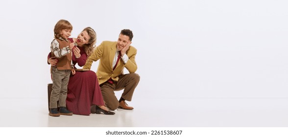 Portrait of young family, mother, father and little son in retro style clothes isolated over white background. Concept of retro style, 60s, 70s, family. Copy space for ad - Shutterstock ID 2261538607