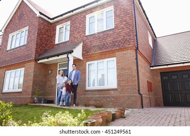 Portrait Of Young Family Standing Outside New Home