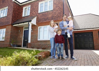 Portrait Of Young Family Standing Outside New Home