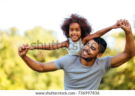 Portrait of young father carrying his daughter on his back