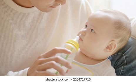 portrait of young father giving milk to baby boy
