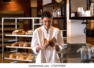 Portrait of young female baker holding bread in her hands at bakery. - Powered by Shutterstock
