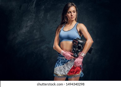 Portrait Of Young Female Boxer With Her Helmet In Hands At Dark Photo Studio.