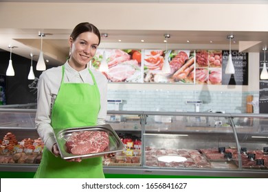 Portrait of young female butcher standing with prepack - Powered by Shutterstock