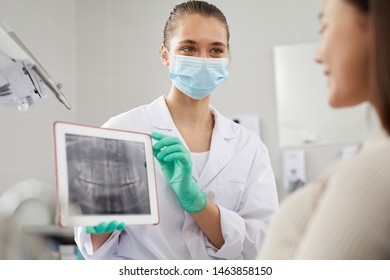 Portrait Of Young Female Dentist Showing Teeth X-ray Image To Patient During Consultation In Clinic, Copy Space