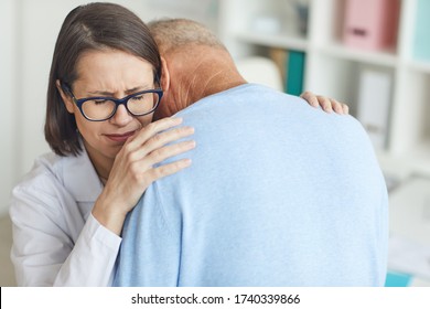 Portrait Of Young Female Doctor Embracing Senior Patient And Crying After Giving Bad News, Copy Space