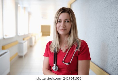 Portrait of young female doctor in red uniform in clinic. Health care concept - Powered by Shutterstock