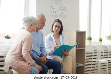 Portrait Of Young Female Doctor Talking To Senior Couple While Sitting In Reception Area Of Modern Clinic, Copy Space