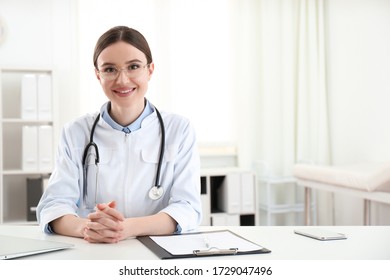 Portrait Of Young Female Doctor In White Coat At Workplace