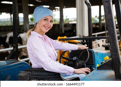 Portrait Of Young Female Farmer Working On Dairy Farm, Driving Small Farm Tractor