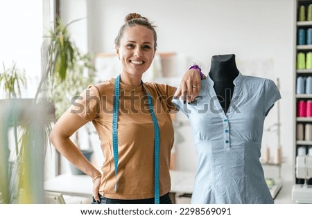 Portrait of young female fashion designer standing at her workplace
