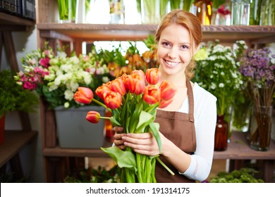 Portrait of young female florist with red tulips looking at camera - Shutterstock ID 191314175