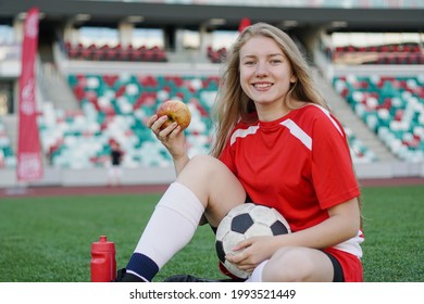 Portrait of young female football player sitting on soccer field with apple after the training - Powered by Shutterstock