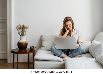 Portrait Of A Young Female Freelancer Sitting On The Couch And Working On Project, Watching Movie On Laptop, Studying, Blogging, Resting And Chatting Online