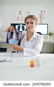 Portrait Of Young Female General Practitioner Showing Lungs X-ray Of Recovered Patient