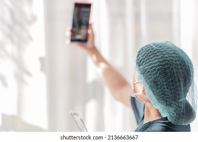 Portrait Of A Young Female Medical Nurse Or Doctor Wearing Protective Mask Taking Selfie On Cellular Device 