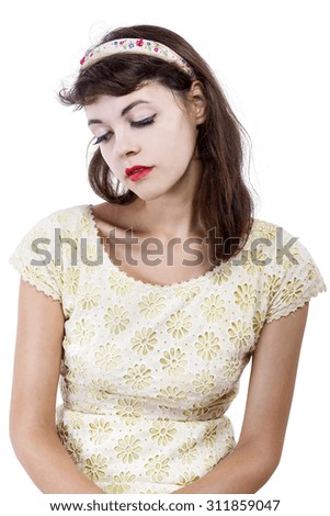Portrait of a young female in old fashioned hairstyle makeup and clothes.  Her make up and hairstyle are fashion from 50s and 60s.  She is isolated on a white background