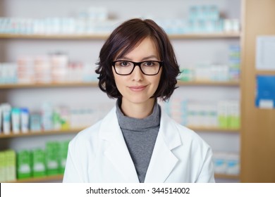 Portrait eines jungen weiblichen Apothekers mit Eyeglasses, der in einem Drugstore steht und der Kamera lächelt.
