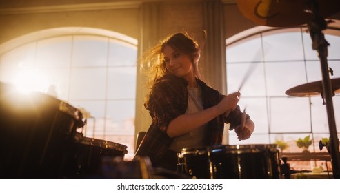 Portrait of a Young Female Playing Drums During a Band Rehearsal in a Loft Studio with Warm Sunlight at Daytime. Drummer Girl Practising Before a Live Concert on Stage in Local Venue.