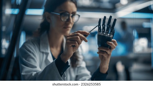 Portrait of Young Female Scientist Working in Technological Research and Development Company, Assembling an Innovative Bionic Prosthetic Hand. Engineer Working on Technology for Physically Impaired - Powered by Shutterstock