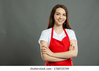 Portrait of young female supermarket employee standing with arms crossed on gray background with copy space advertising area