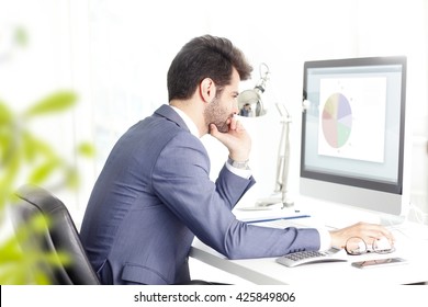 Portrait Of Young Financial Businessman Sitting In Front Of Computer And Thinking To Solve The Problem. 