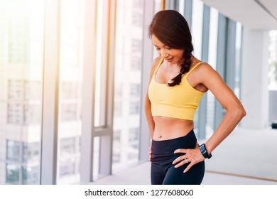 Portrait Of Young Fit Asian Woman Standing In Gym, Hands On Hips Pose. Fitness Female Model Image