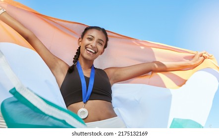 Portrait Of A Young Fit Indian Female Athlete Cheering And Holding India Flag After Competing In Sports. Smiling Fit Active Sporty Woman Feeling Motivated And Celebrating