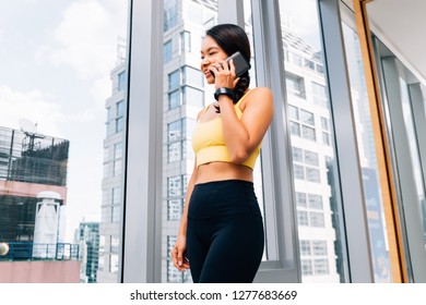 Portrait of young fit woman talking on the hone at high rise gym. Female fitness model image - Powered by Shutterstock