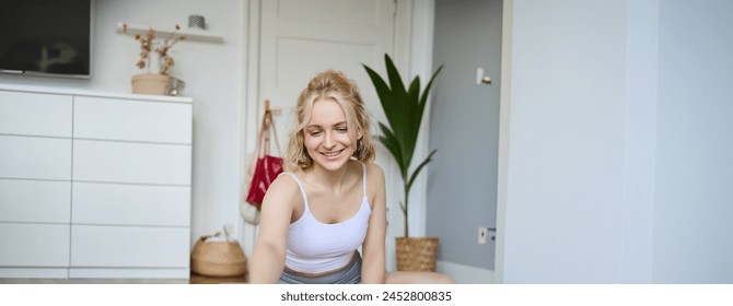 Portrait of young fitness instructor, vlogger creating content at home, doing workout and record exercises on digital camera, using rubber yoga mat. - Powered by Shutterstock