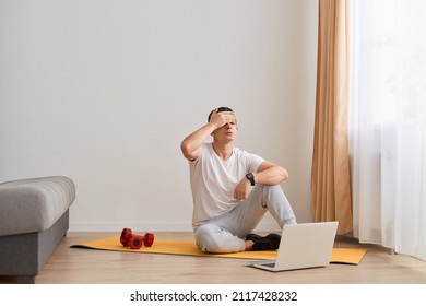 Portrait of young fitness man being frustrated and desperate, angry and sad with hands on head, suffering headache after or during sport workout at home. - Shutterstock ID 2117428232