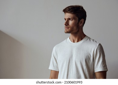 Portrait of young focused caucasian man looking away. Handsome brown hair guy wearing t-shirt. Concept of male beauty. Isolated on white background with shadow in studio. Copy space - Shutterstock ID 2100601993