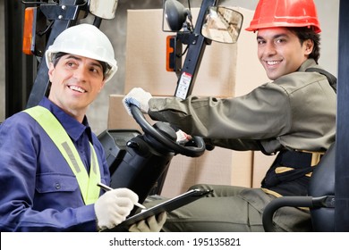 Portrait Of Young Forklift Driver With Supervisor Writing Notes At Warehouse