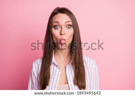Portrait of young funky childish joyful girl woman stick tongue out on camera isolated on pink color background