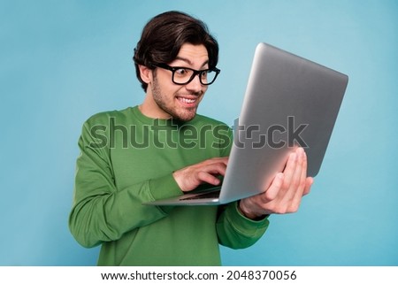 Portrait of young funky funny geek nerd smiling businessman working in netbook isolated on blue color background