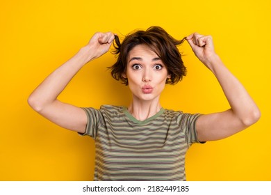 Portrait of young funny lady pouted lips touching curls playful showing hair isolated on bright yellow color background