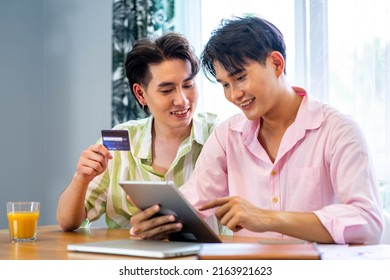 Portrait Of Young Gay Couple, Lgbt Man Holding Credit Card Enjoy Shopping Online With Laptop At Home. LGBT And Love Concept.