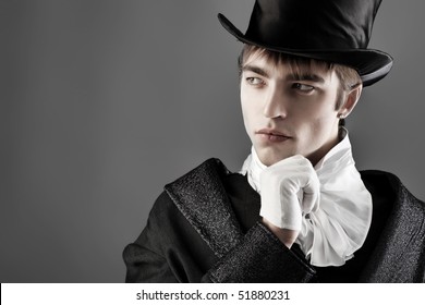 Portrait of a young gentlemen wearing dinner jacket and black top hat. Shot in a studio.