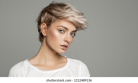 Portrait of young girl with blond short hairstyle looking at camera isolated on gray background with copy space 